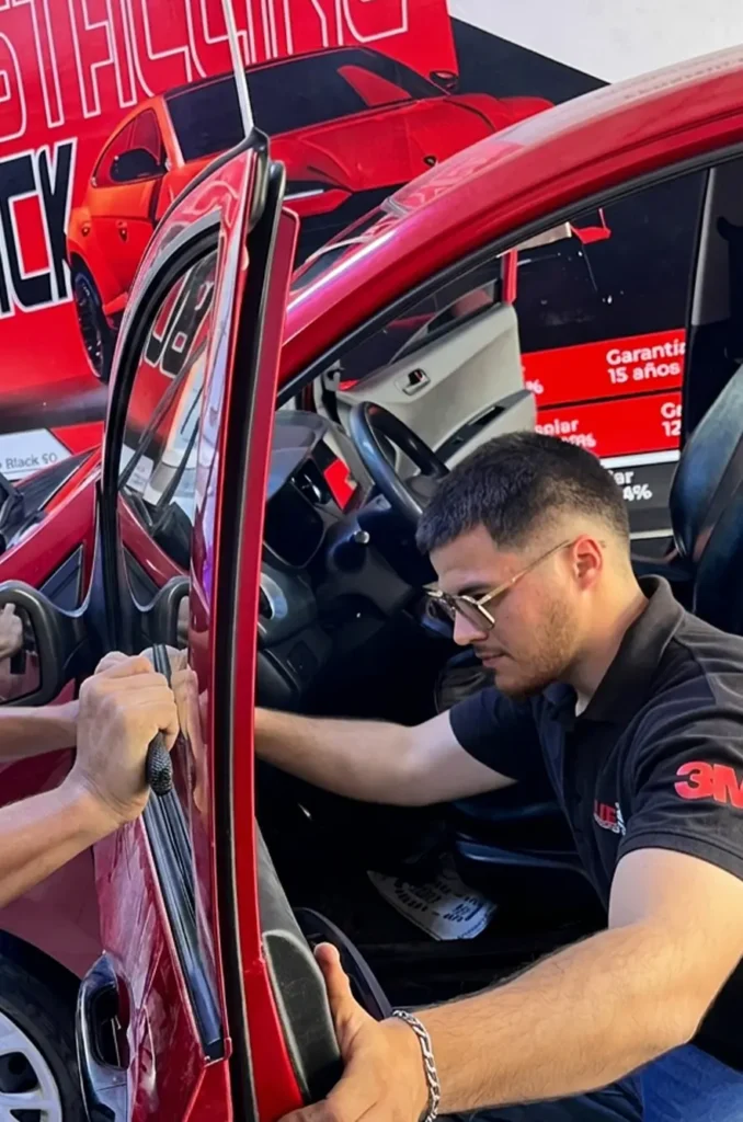 Técnico experto aplicando lámina de seguridad certificada 3M en MJE Polarizados La Victoria.